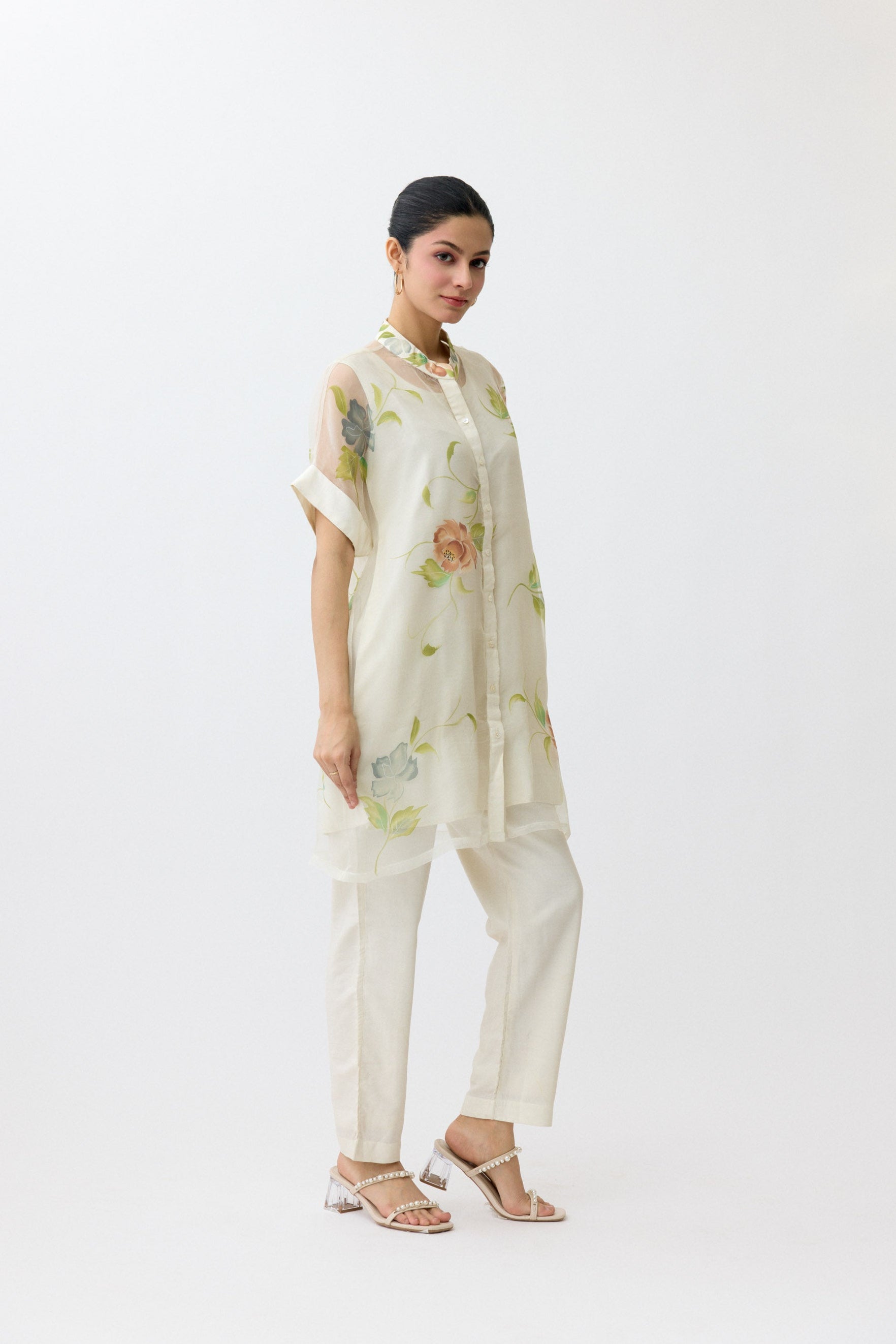 Woman wearing a light-colored outfit with floral patterns on a white background