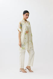 Woman wearing a light-colored outfit with floral patterns on a white background